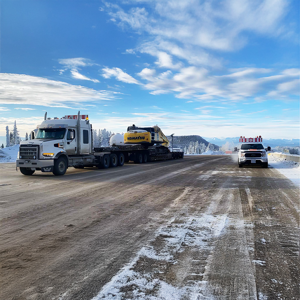 ACL transporting heavy equipment through a snowy mountain landscape in Western Canada