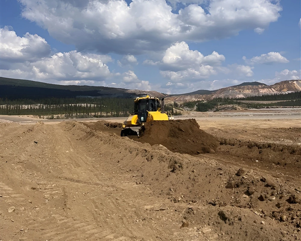 Dozer grading a road construction site in a broad mountain valley