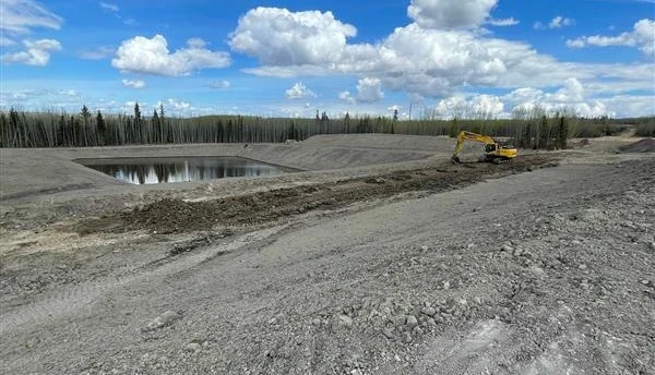 Prepared site access and water storage area with an excavator in the distance