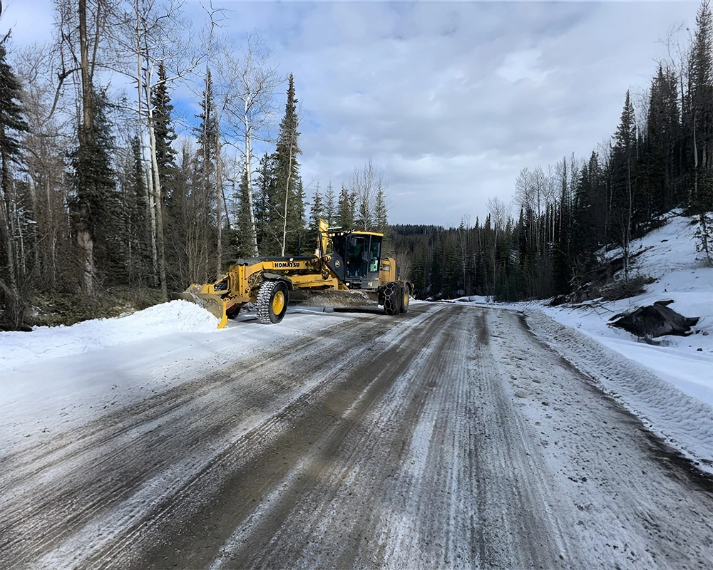 Grader clearing snow from a forest access road